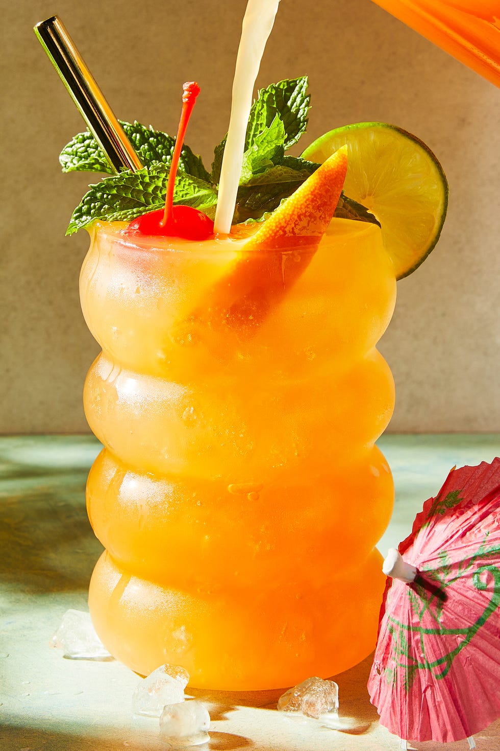 Punch au rhum cocktail au rhum et punch dans un verre avec de la menthe, une tranche d'orange, une rondelle de citron vert et une cerise au marasquin
