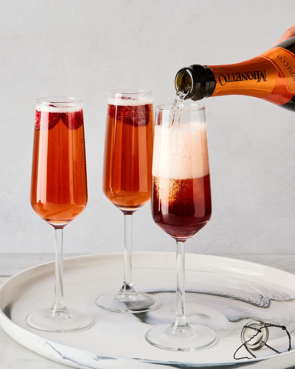 trois flûtes en verre remplies de champagne, de liqueur de cassis et de framboises fraîches