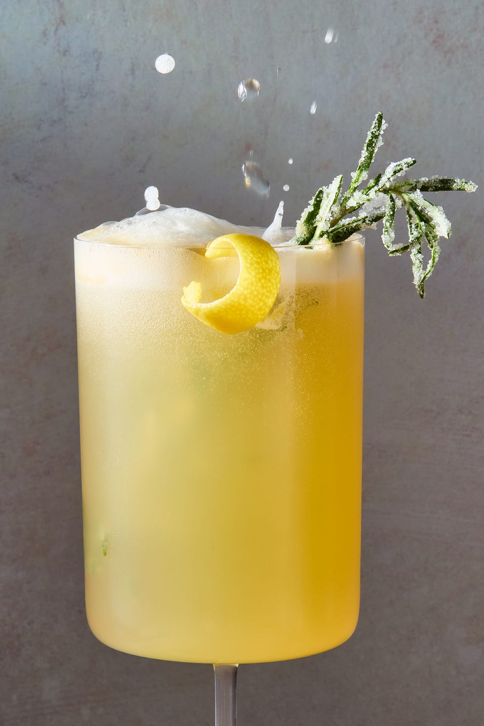 spritz de cocktail sans alcool aux genoux d'abeille avec un zeste de citron et du romarin sucré