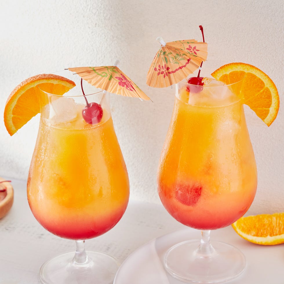 Sexe sur la plage Sexe rouge et orange sur le cocktail de plage garni d'une tranche d'orange, d'une cerise de marasquin et d'un parapluie de cocktail